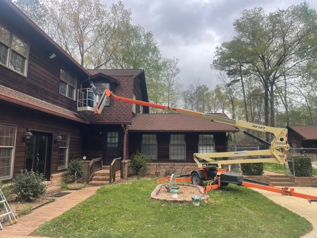 Lift positioned beside a Jasper, Alabama home during a carpenter bee treatment and wood-hole sealing project.